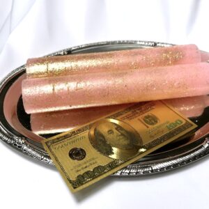 A silver tray with two candles and a gold dollar bill.