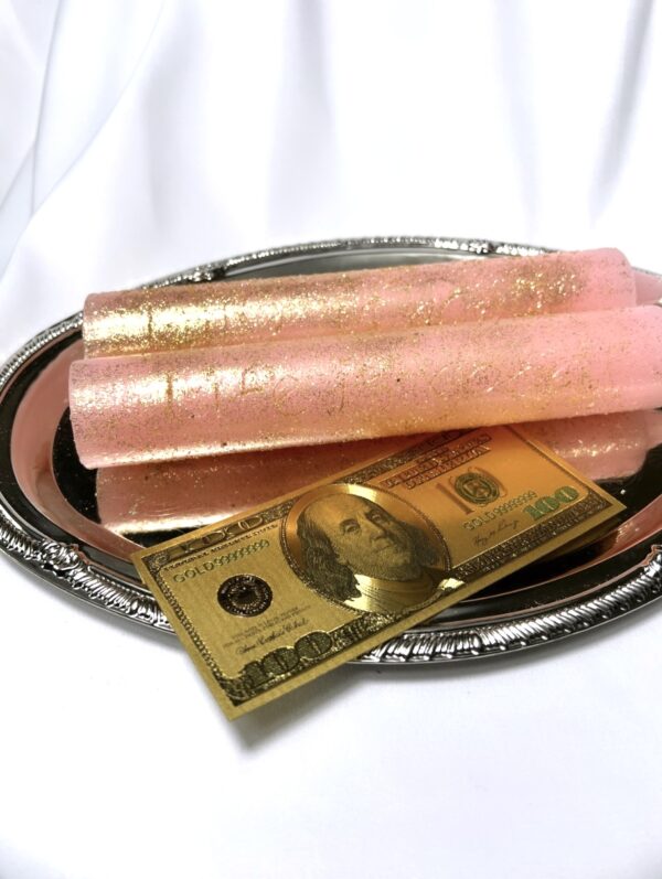 A silver tray with two candles and a gold dollar bill.