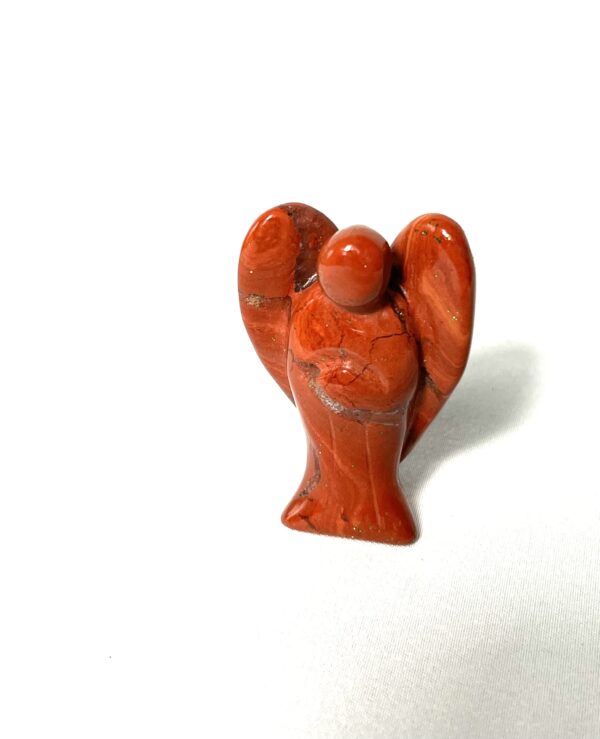 A red clay figurine of an angel with arms outstretched.