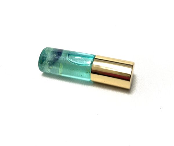 A green and gold tube of lipstick on top of a white surface.