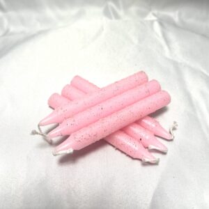 A group of pink candles on top of white cloth.