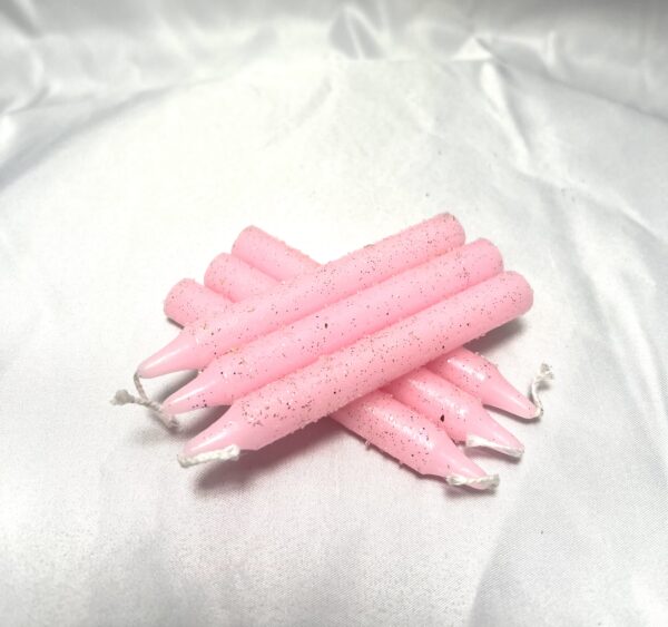 A group of pink candles on top of white cloth.