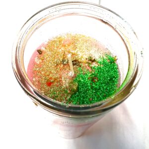 A jar of sand and green grass in it.