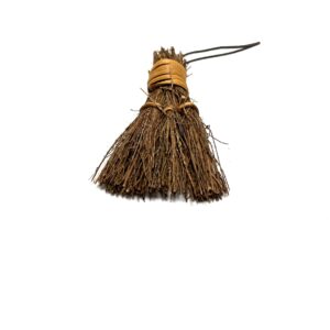 A small broom is hanging on the wall.