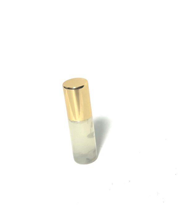 A small glass bottle with gold cap on top of it.