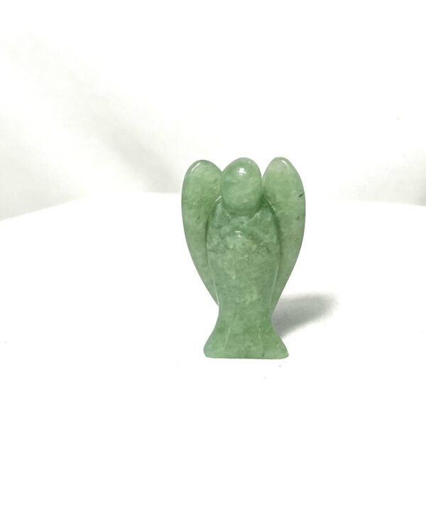 A green stone angel statue sitting on top of a table.