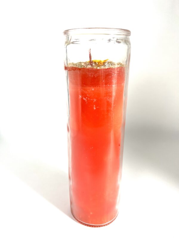 A candle in a glass with orange wax.