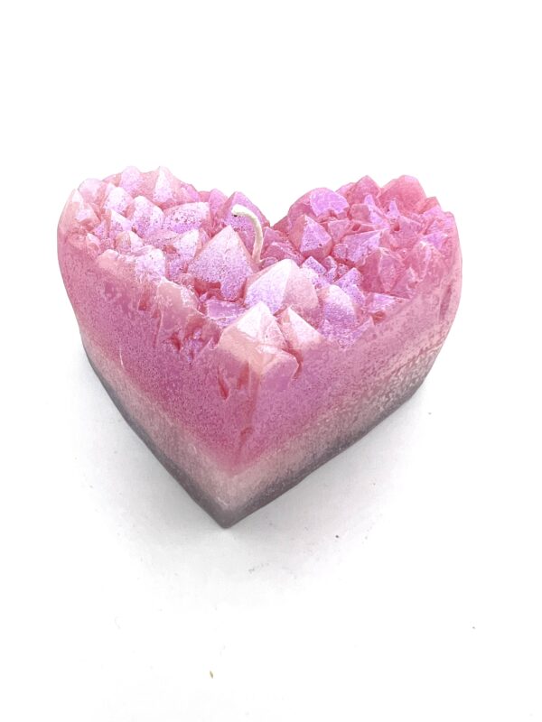 A pink heart shaped soap with white and purple sprinkles.