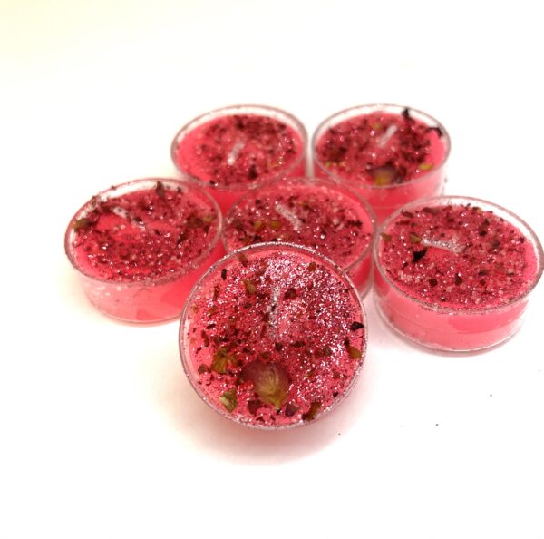 A group of six pink tea lights sitting on top of each other.