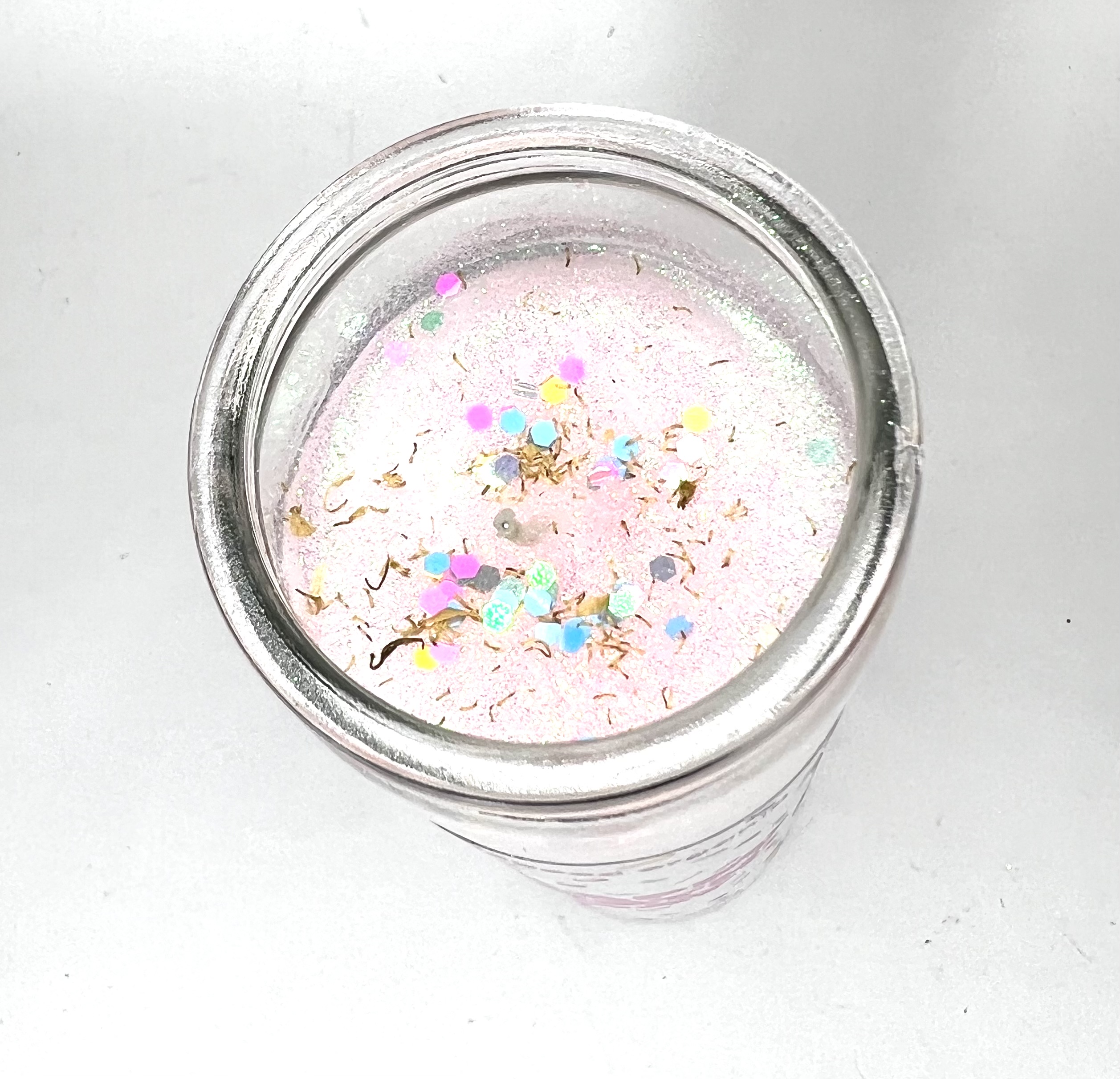 A glass of liquid with some colorful sprinkles on it