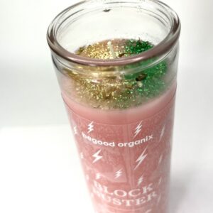 A glass of pink liquid with green grass in it.