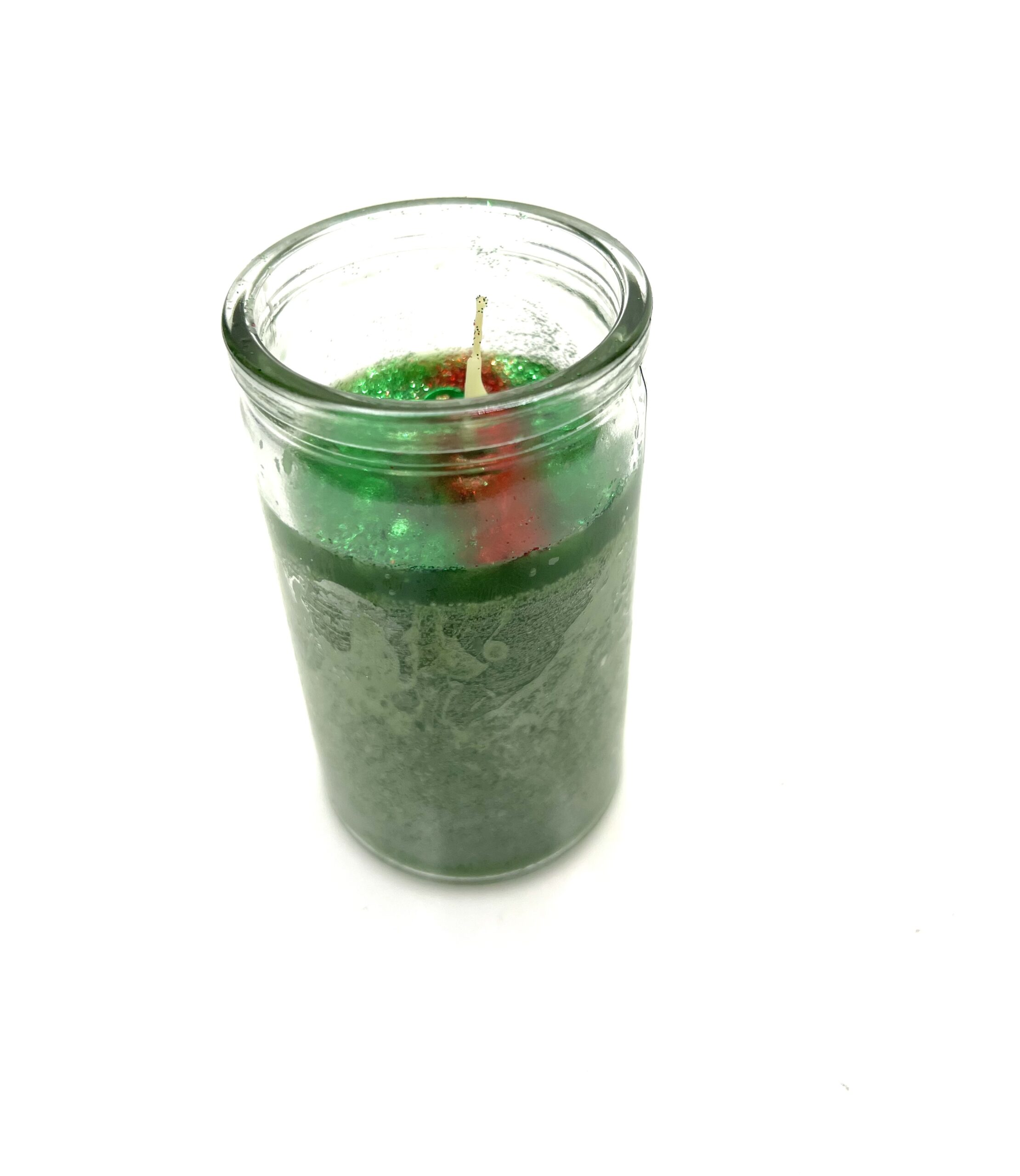 A candle in a glass jar with green wax.