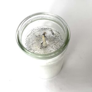 A candle in a glass jar with some wax.