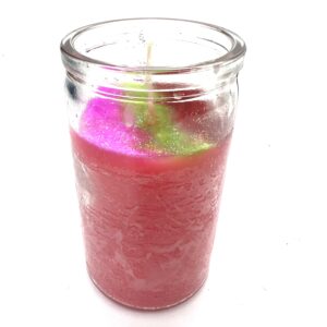 A candle in a glass jar with pink and green candles.