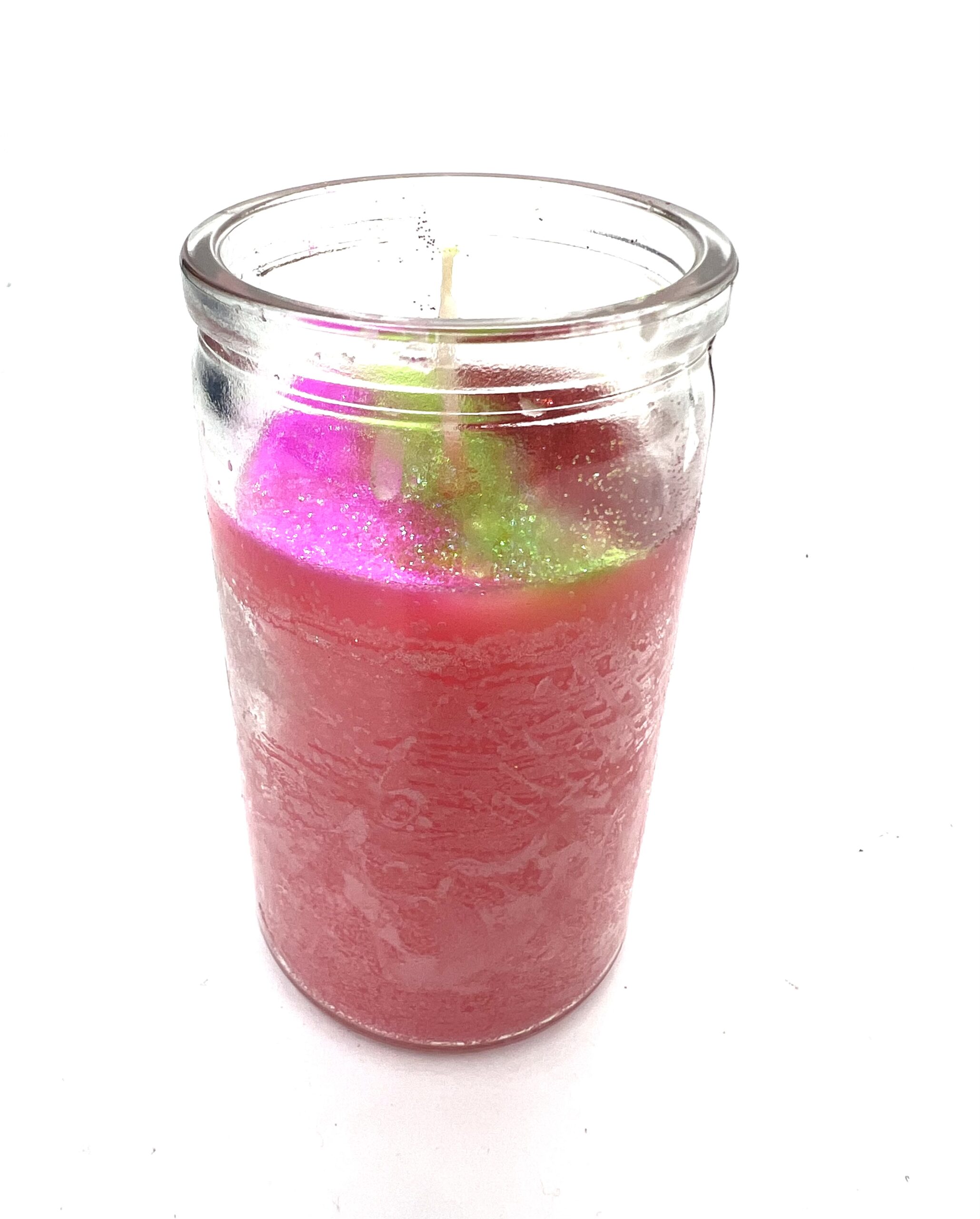 A candle in a glass jar with pink and green candles.