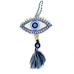 A blue and white evil eye hanging from a gray tassel.