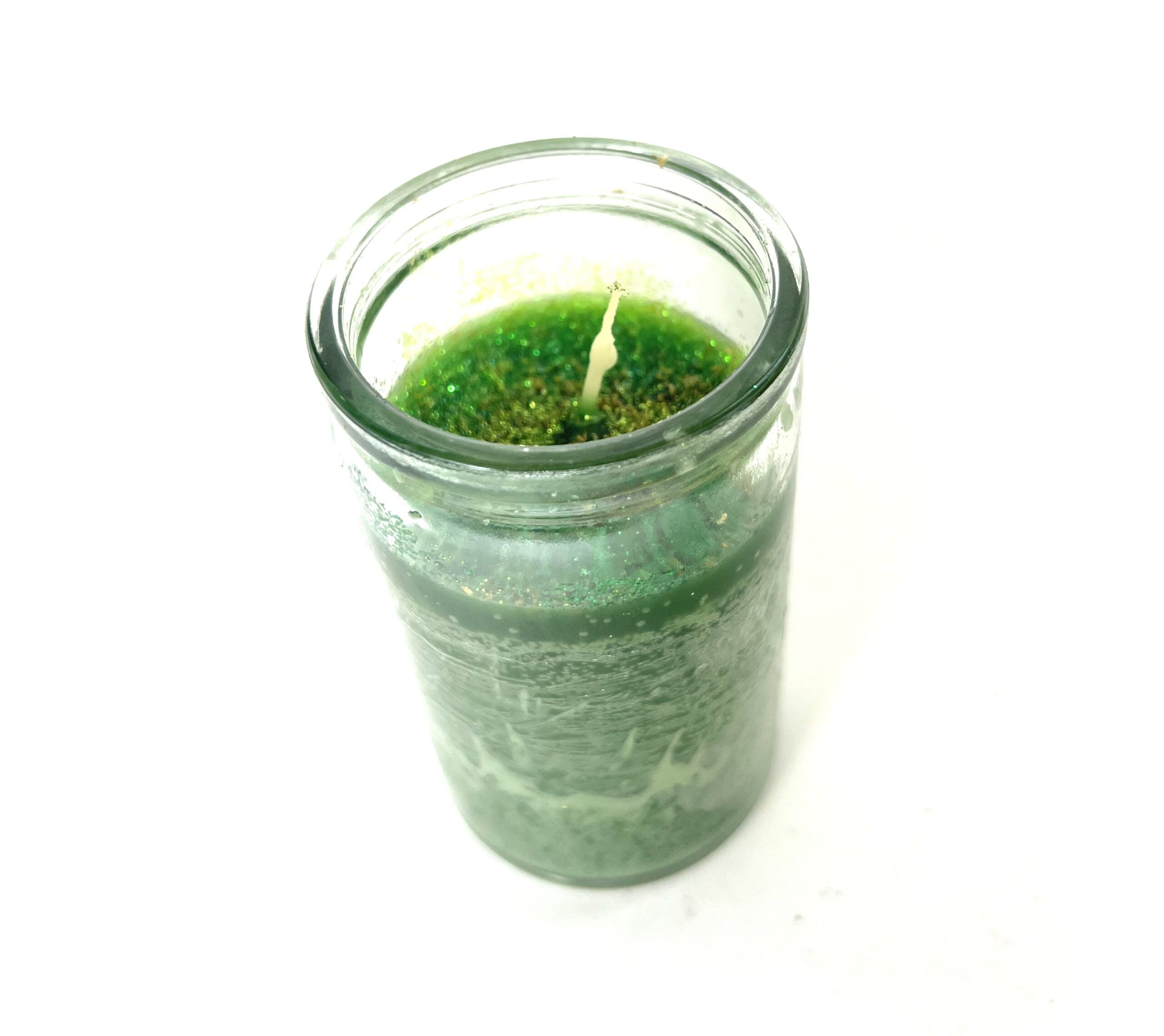 A candle in a jar with green moss on it.