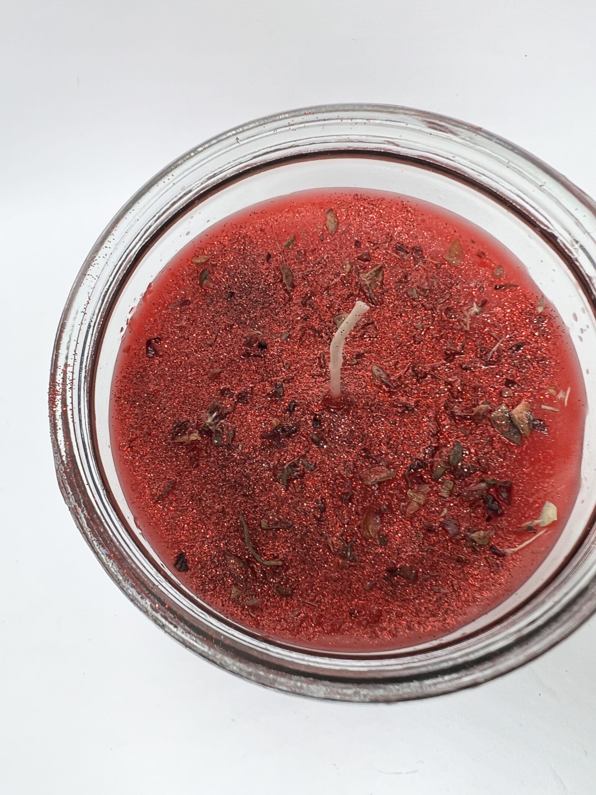 A jar of red liquid with some herbs in it