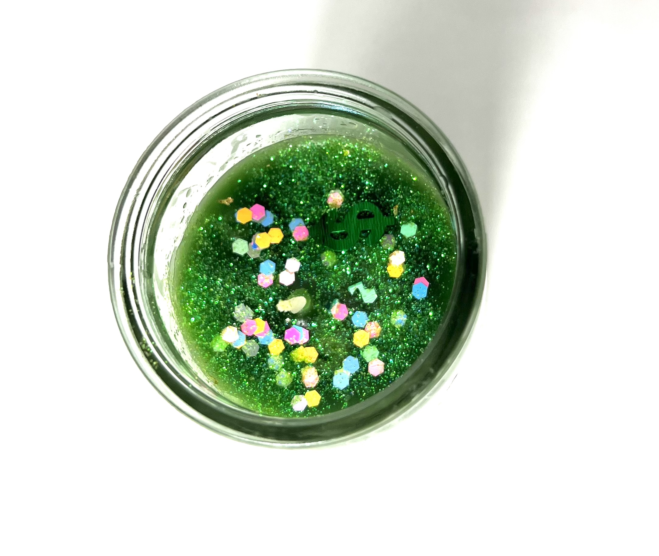 A jar of green liquid with sprinkles in it.