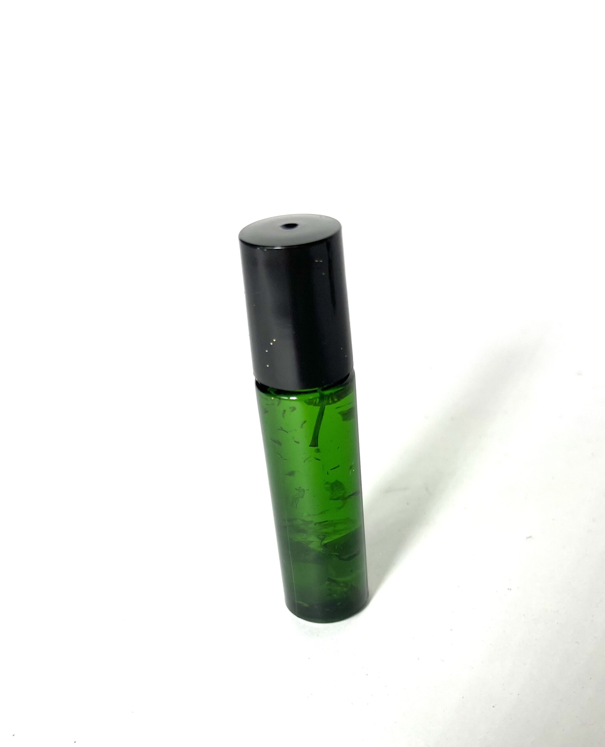 A green bottle with black cap on white surface.