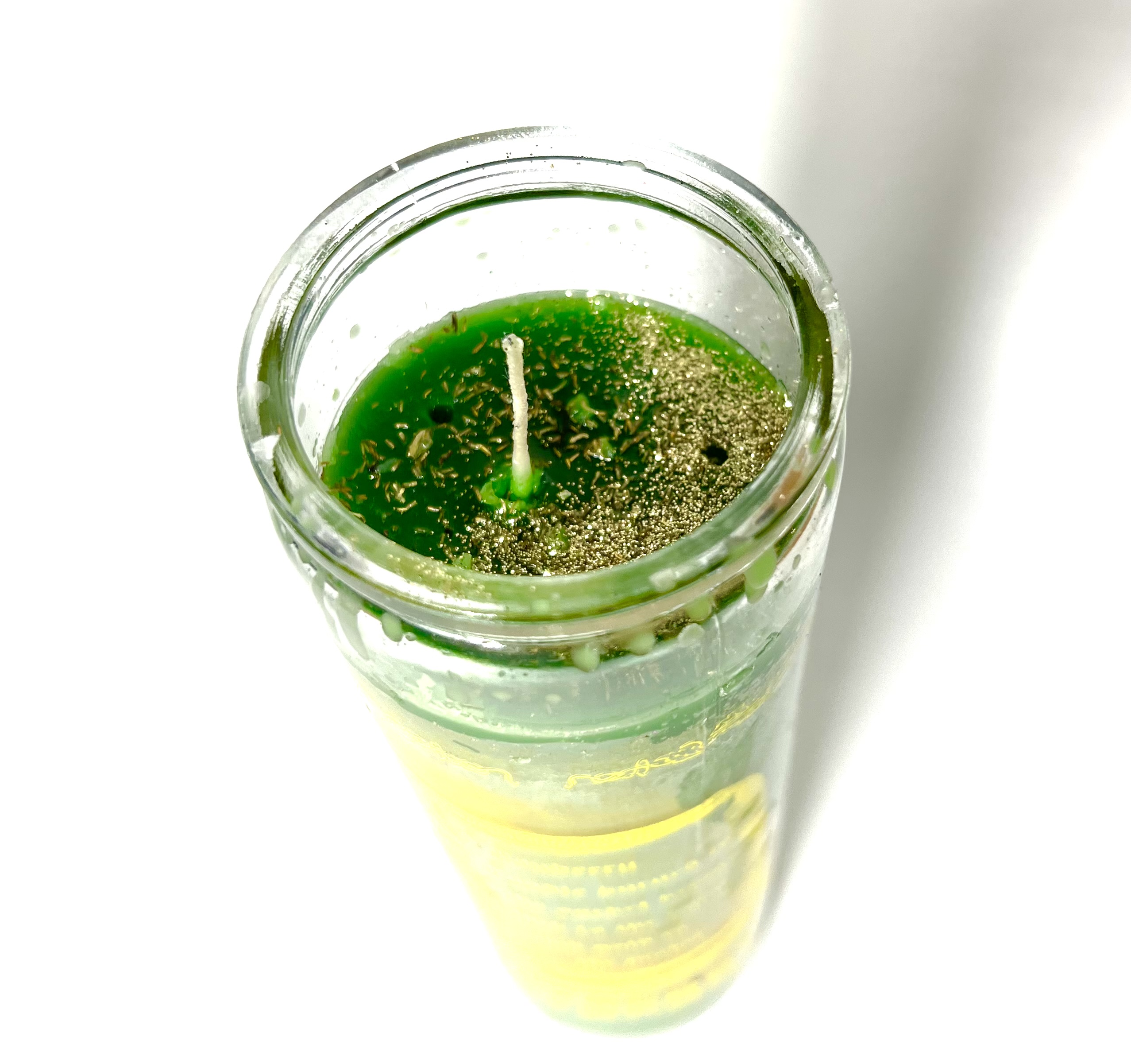 A candle in a glass with green wax.