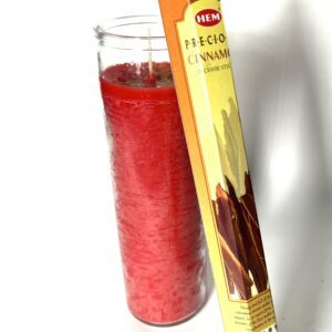 A candle and some sticks of cinnamon are next to each other.