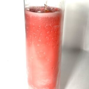 A glass of pink liquid with ice in it.