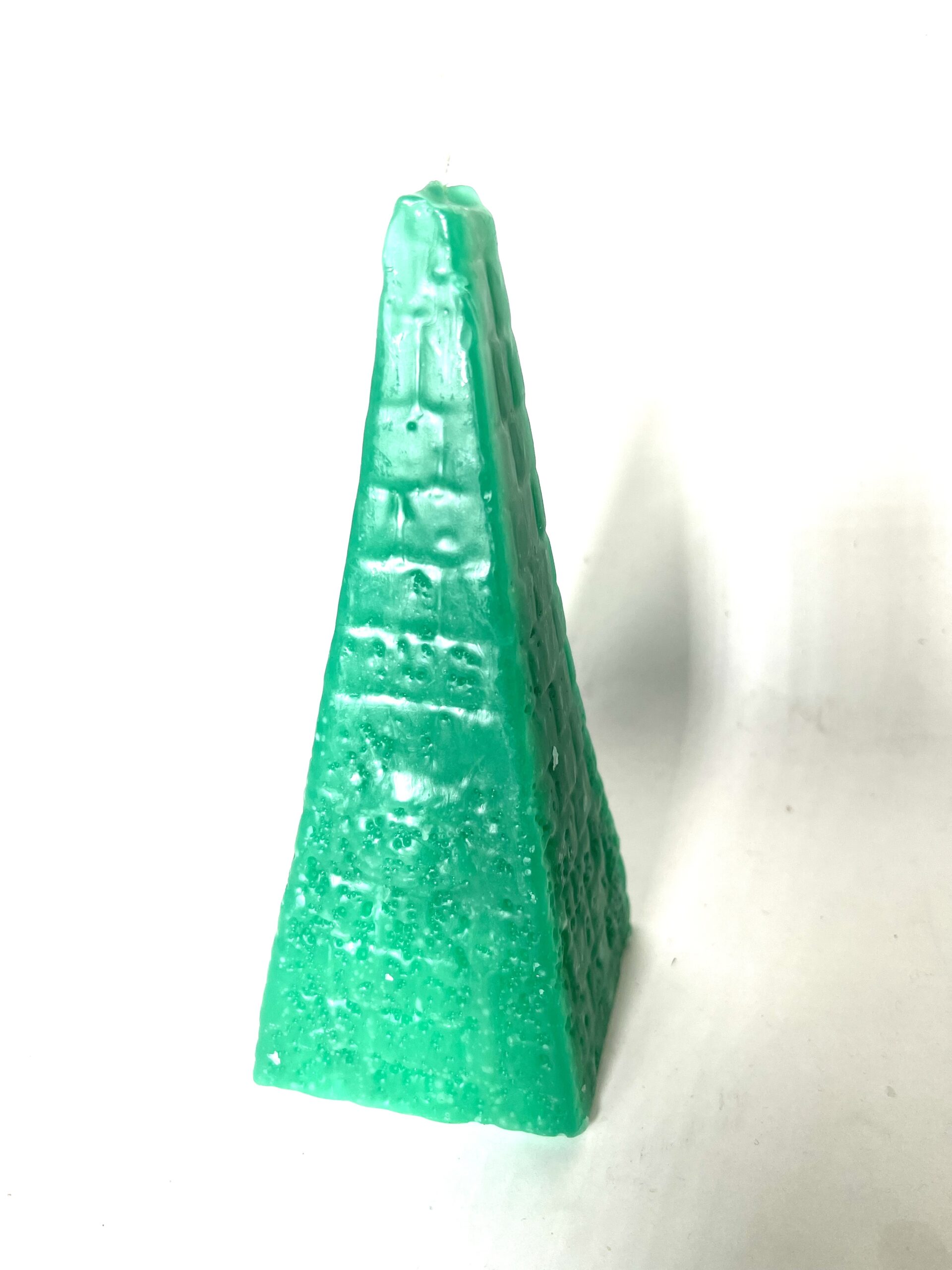 Green pyramid-shaped candle on white background.