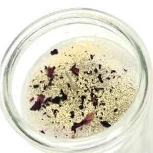 A glass jar containing a clear liquid with floating herbs and spices.