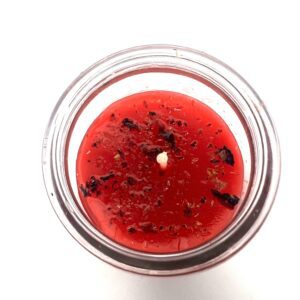 Top view of a red candle with burnt wick in a glass container.
