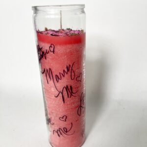 A red candle in a glass jar with handwritten messages.
