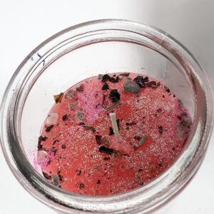 A partially melted red candle in a glass container.