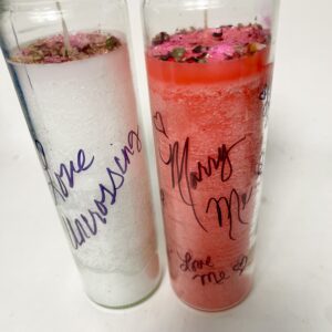 Two tall candles with romantic inscriptions, one white and one red.